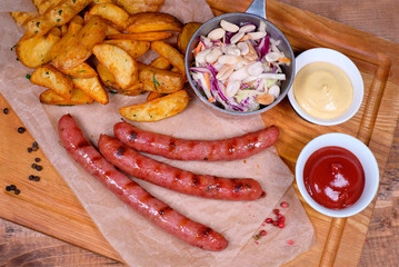 Composition with hot dogs, french fries and sauce on wooden board, top view