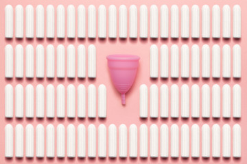 Reusable silicone menstrual cup and tampons comparison on a soft pink background. Modern female...