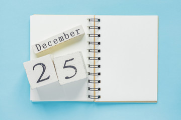 25 december on a wooden calendar on a textbook on  blue background. christmass and new year concept