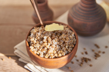 cooked buckwheat with a slice of butter served with rye crisps on wooden table