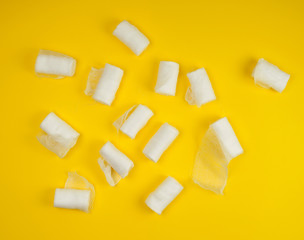 rolled up white sterile medical bandages on a yellow background