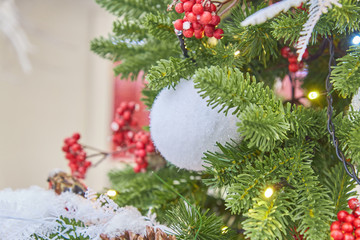 close up of christmas tree decorated with sparkling balls and garland with lights on. Festive background with copy space for your projects
