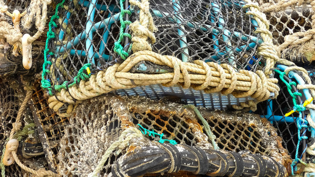 Close up of stacked commercial fishing lobster pots. With ropework netting knots and ties. Empty, showing signs of regular use. Landscape image with space for copy. Cornwall.