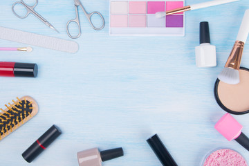 on a light background, in the center with a place for the inscription, arranged in a circle items for manicure and makeup, nail polishes, scissors, saw, colored shadows, face powder with 