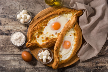 Traditional Adjarian Georgian khachapuri with cheese and egg on wooden table. Top view