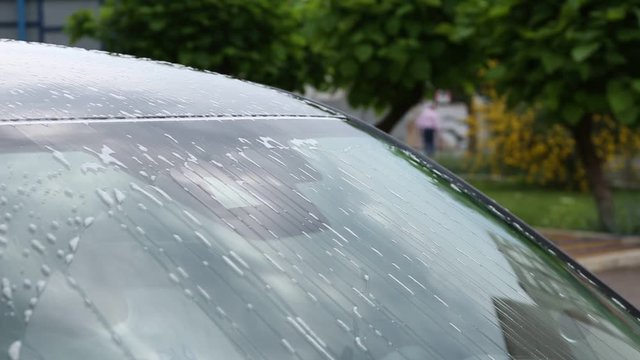 Washing car windscreen with wipers and liquid, closeup