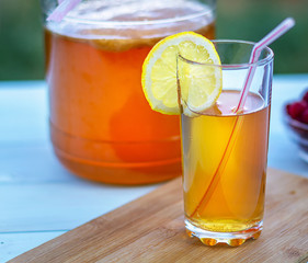 Glass jar with Kombucha, poured glass with Kombucha and raspberries in the summer garden.