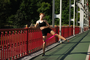 Happy athletic woman doing stretching workout with the rubber resistance band. Empty space