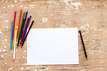 Obraz premium Blank paper and colorful pencils on the wooden table. View from above