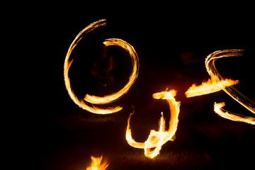 The artist shows a fire show at night spinning torches, circles of fire and loops