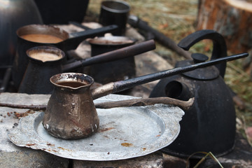 Boiling coffee in turkish cezva on a grate over a burning bonfire, a camping concept