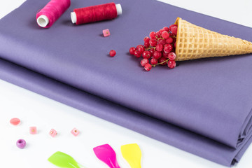 The cut of violet fabric on a white background is complemented with the scattered buttons of pink...