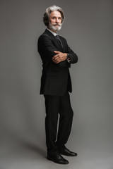 Obraz na płótnie Canvas Full length image of caucasian adult businessman wearing formal black suit standing at camera with arms crossed