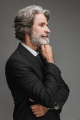 Image in profile of caucasian adult businessman wearing formal black suit looking aside at copyspace