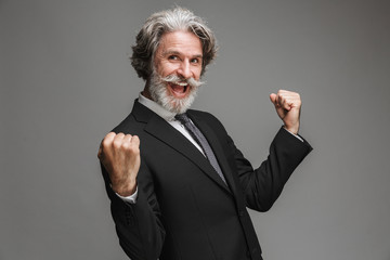 Image of joyful adult businessman wearing formal black suit rejoicing and clenching fists