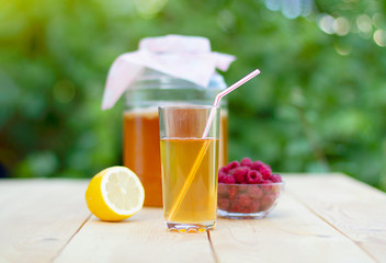 Glass jar with Kombucha, poured glass with Kombucha and raspberries in the summer garden.