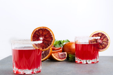 Blood orange margarite, slices of exotic orange, mint on the grey table against white backgound