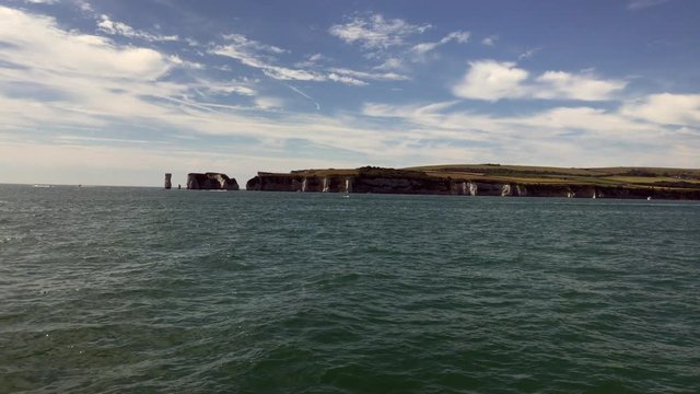 Old Harry Rocks filmed from sailing yacht on calm sunny day. Old Harry Rocks near Studland on the Jurassic coast, UK.