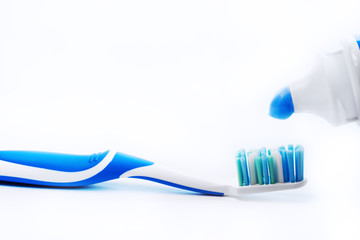 Close up view of transparent toothbrush with blue bristles and toothpaste on white background. Healthy teeth, dental care concept. Space for text.