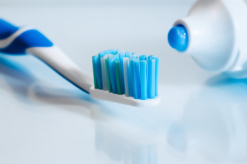 Close up view of transparent toothbrush with blue bristles and toothpaste on white background. Healthy teeth, dental care concept. Space for text.