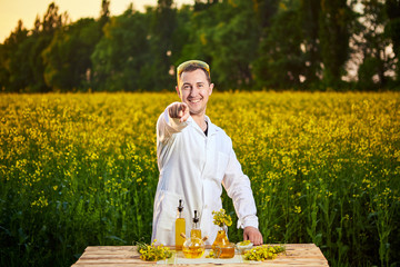 A young man biologist or agronomist examines the quality of rapeseed oil on a rape field....