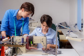 Two female tailors at working process in workroom. Small business concept.