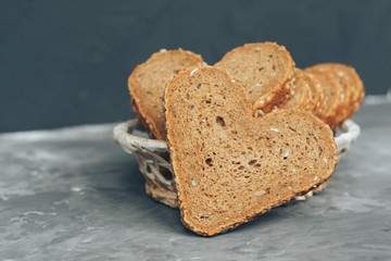 Rye bread in the shape of heart cut into slices on a gray background