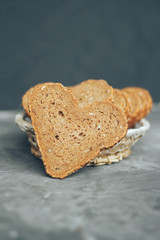 Rye bread in the shape of heart cut into slices on a gray background