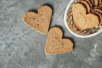 Rye bread in the shape of heart cut into slices on a gray background