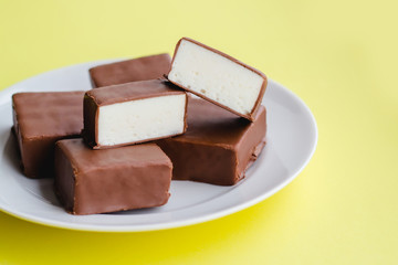 Chocolate sweets with white souffle on a plate on a yellow background.