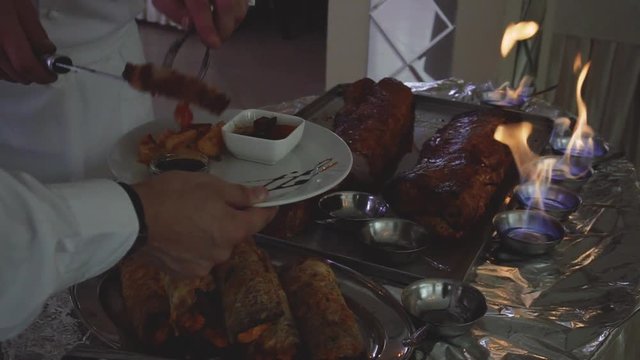 chef cuts roast meat near the fire