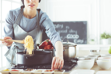 Cooking woman in kitchen with wooden spoon