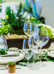 Wedding party dinner table setting with tableware and silverware and glasses set and Candlestick and flower in restaurant.