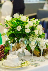 Christmas party dinner table setting with tableware and silverware and glasses set and Candlestick and flower in restaurant.