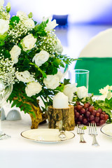 Wedding party dinner table setting with tableware and silverware and glasses set and Candlestick and flower in restaurant.