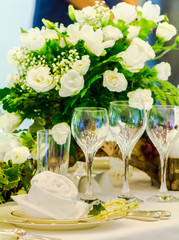 Thanksgiving party dinner table setting with tableware and silverware and glasses set and Candlestick and flower in restaurant.