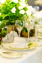 Wedding party dinner table setting with tableware and silverware and glasses set and Candlestick and flower in restaurant.