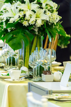 Christmas party dinner table setting with tableware and silverware and glasses set and Candlestick and flower in restaurant.