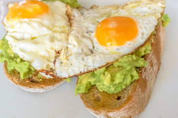 Two fried eggs on mashed avocado on thick wholemeal toast