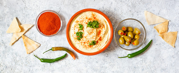 Healthy homemade hummus served with paprika powder, pita bread, olives and parsley. Middle Eastern cuisine, Israeli cuisine, Levanese cuisine, Levantine cuisine. Light background. Top view