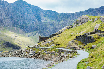 Views of beautiful lake in Snowdonia National Park, North Wales, mountains on the back, stone wall, miners track, selective focus