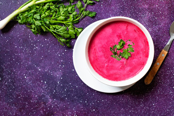 Cold Creamy Beetroot Soup, Beetroot Gazpacho Served in a White Plate with Bread and Fresh Herbs. Bright Purple Background. Vegetarian, Clean Eating Food Concept. Copy Space. Top View