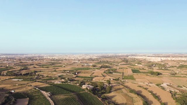 Aerial video flying forward over the Buskette terraced fields and agricultural farmlands of the Siggiewi region of Malta
