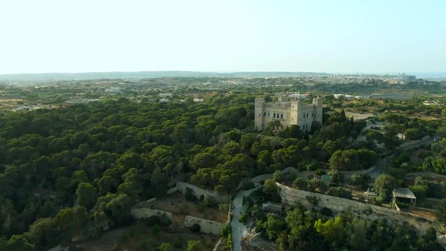 Slow forward flight aerial video of the Palace of Verdala and the terraced Buskette fields below. Malta.