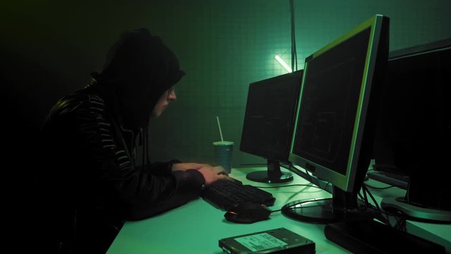 Male hacker in a hood works on a computer. In 4k
