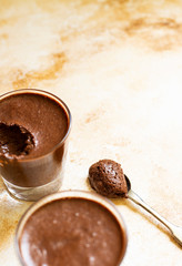 Chocolate souffle or mousse on a light marble vintage background, with a vintage copper spoon. Dessert in a spoon. Close-up. Space for text. Vertical. Selective focus