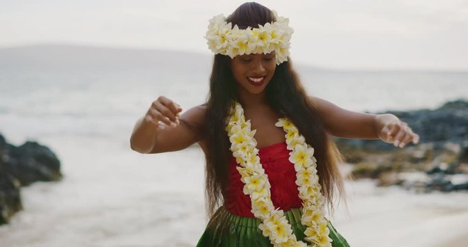 Beautiful woman performing a Hawaiian Hula 'Auana dance on the beach in slow motion