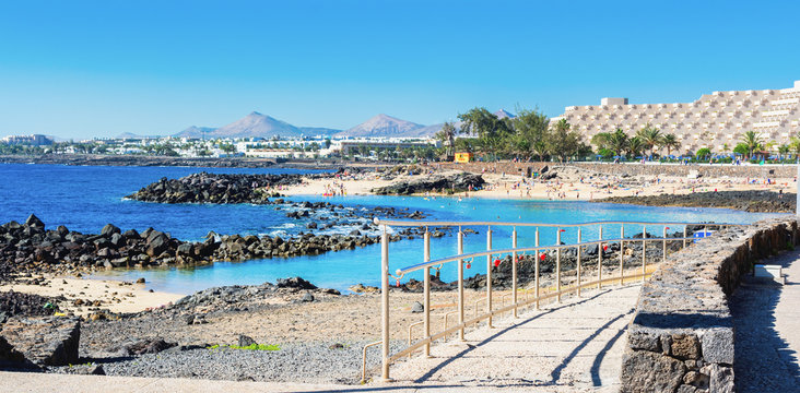 Lagoon with turquoise clear water in Playa Jablillo beach, in Costa Teguise, Lanzarote, Canary islands. Sandy beach with blue sea, volcanic rocks