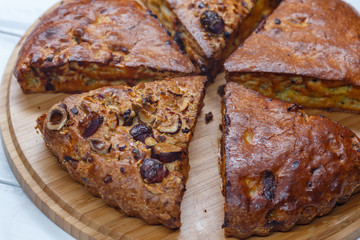 homemade banana pie with nuts, dried apricots and raisins, cut into pieces, on a wooden board