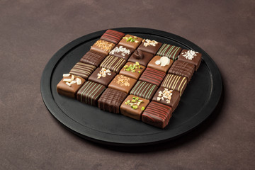 chocolates variety in black tray on brown background